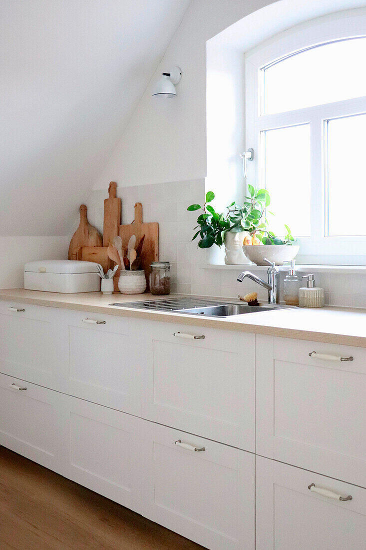 White kitchen cabinets and worktop with wooden chopping boards and bread box