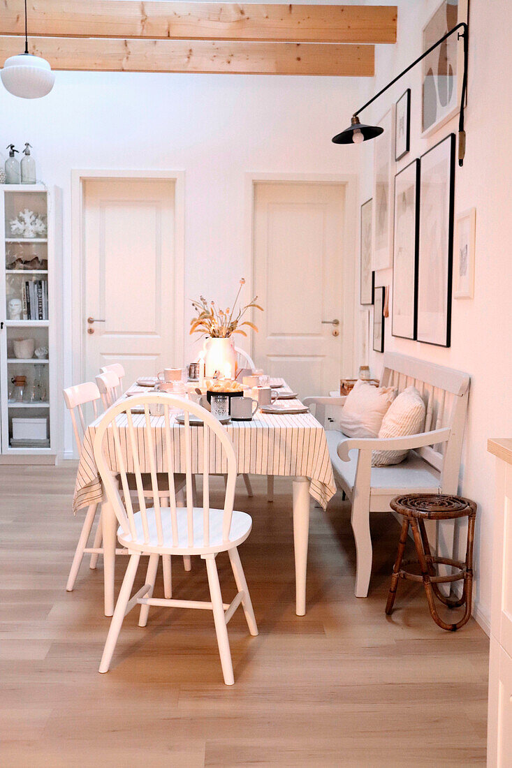 Scandinavian-style dining area with white wooden table, chairs and bench seat