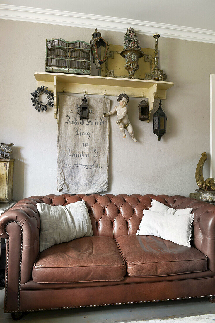 Antique bric-a-brac on shelf above vintage leather couch