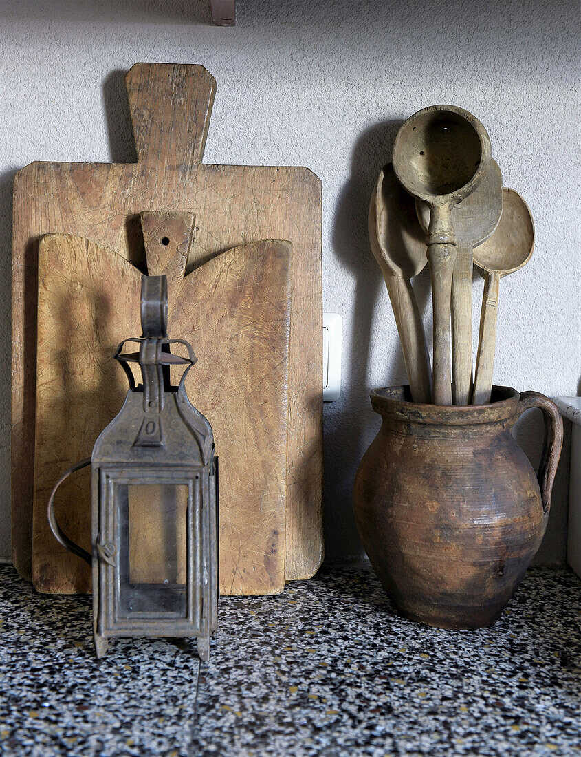 Old wooden boards, small metal lantern and jug with wooden spoons