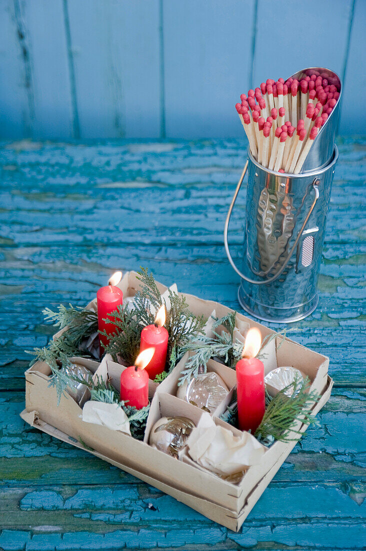 Carton with old baubles and red candles, matches
