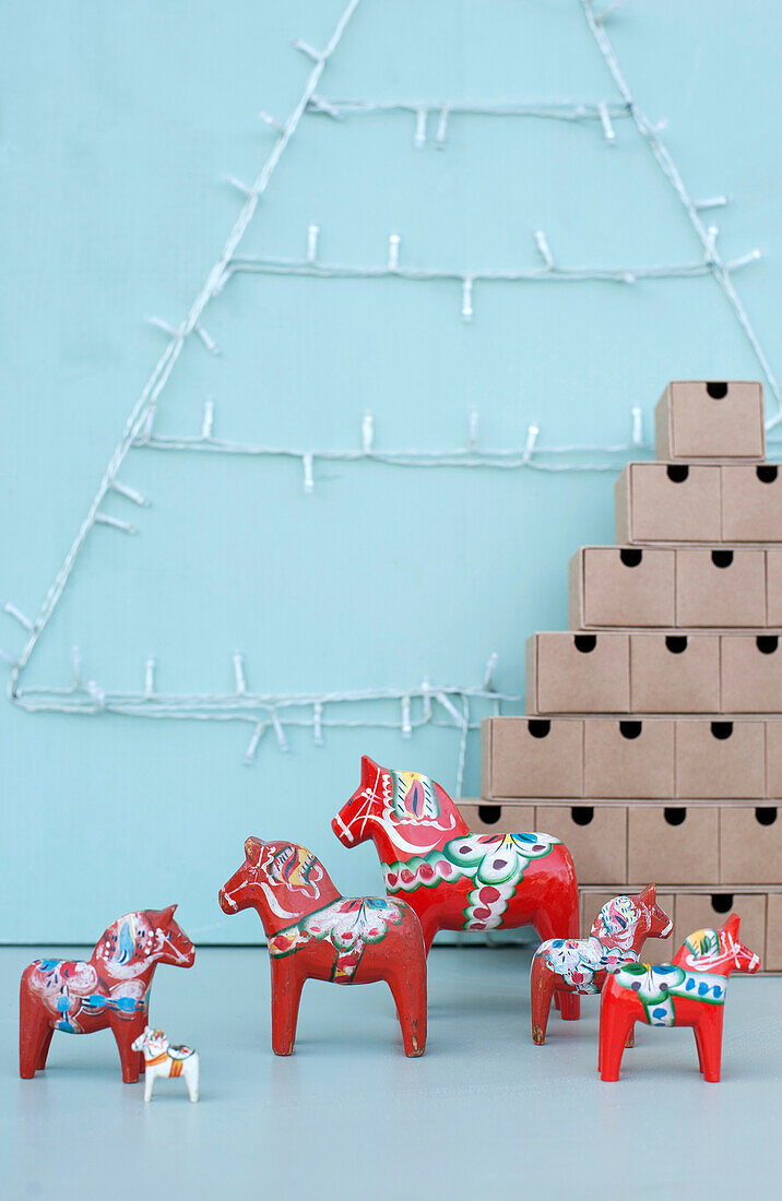 Red Dala horse figurines, stack of cardboard boxes and Christmas lights