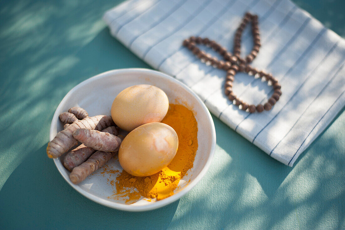 Bowl with turmeric roots, turmeric powder and unpainted Easter eggs