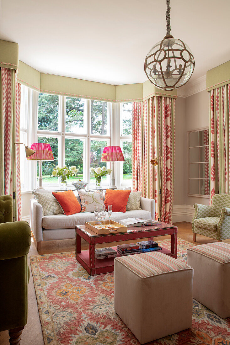 Klassisches Wohnzimmer mit Erkerfenster, eleganten Vorhängen und beigefarbenen Sofa