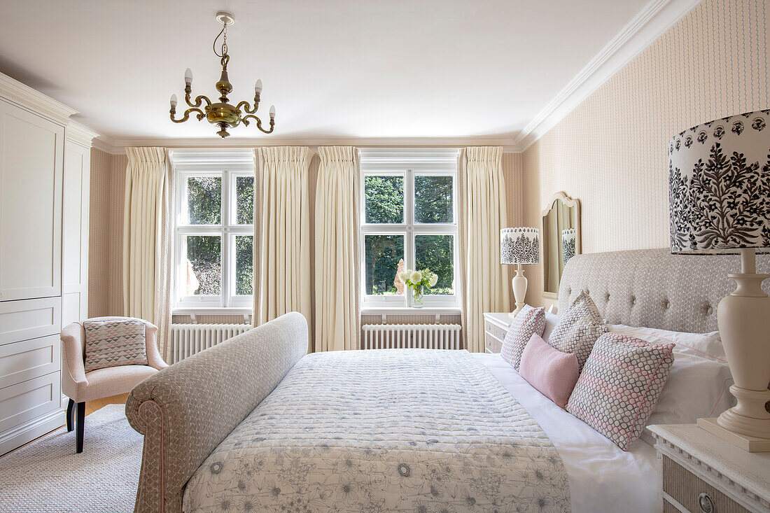 Bedroom in pastel colors with patterned bedding and chandelier