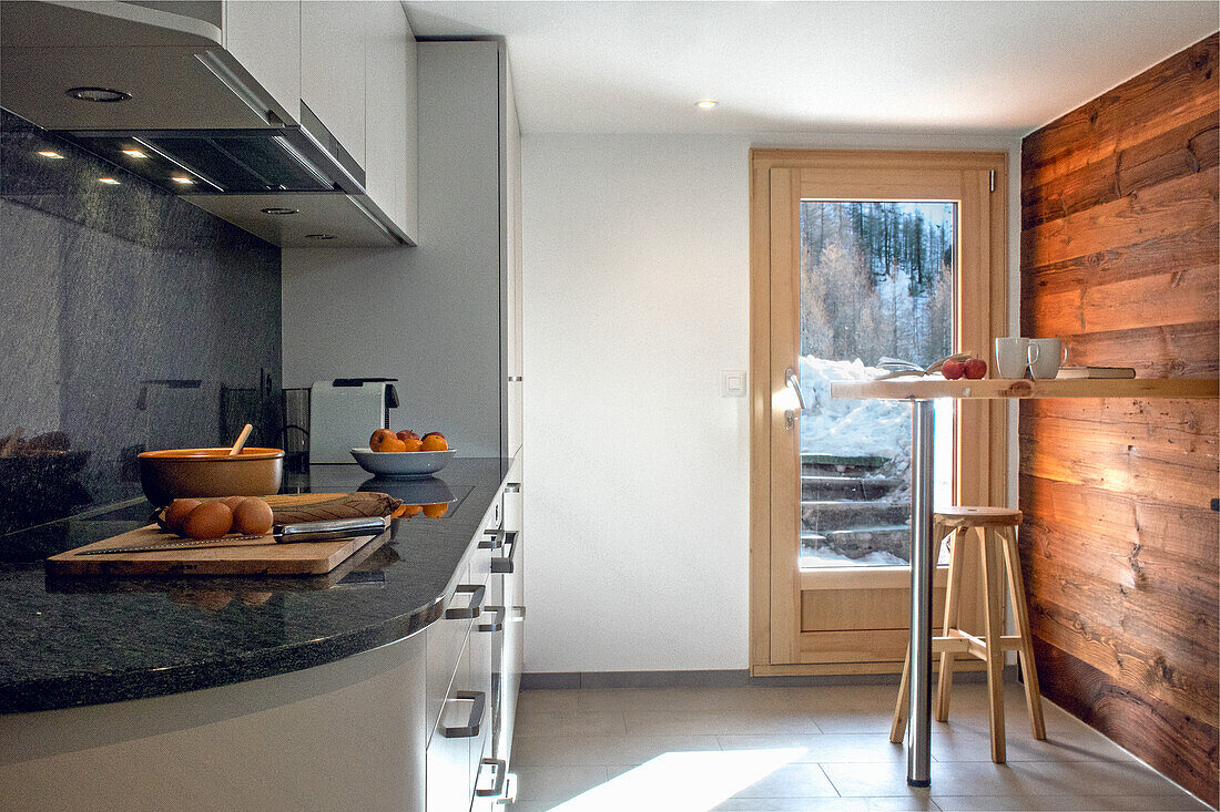 Modern kitchen with wooden elements and a view of the snow-covered landscape