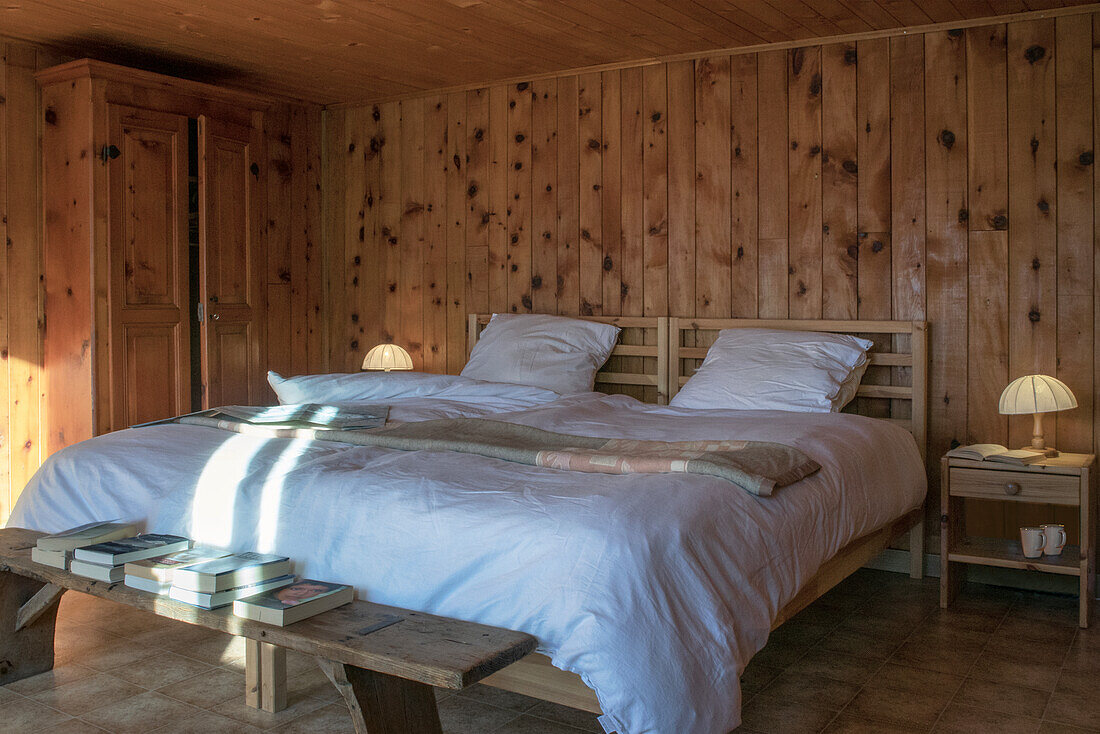 Holzvertäfeltes Schlafzimmer mit weißer Bettwäsche und Nachttischen