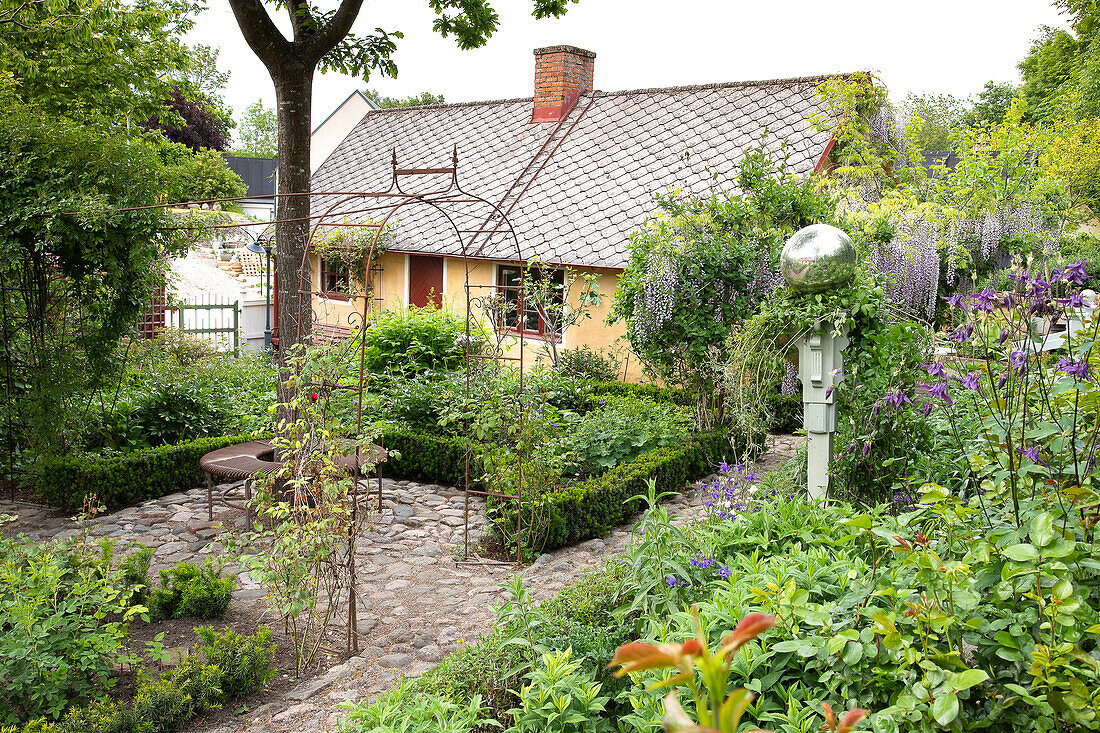Blick auf Garten mit Wegen aus Kopfsteinpflastern und auf Haus