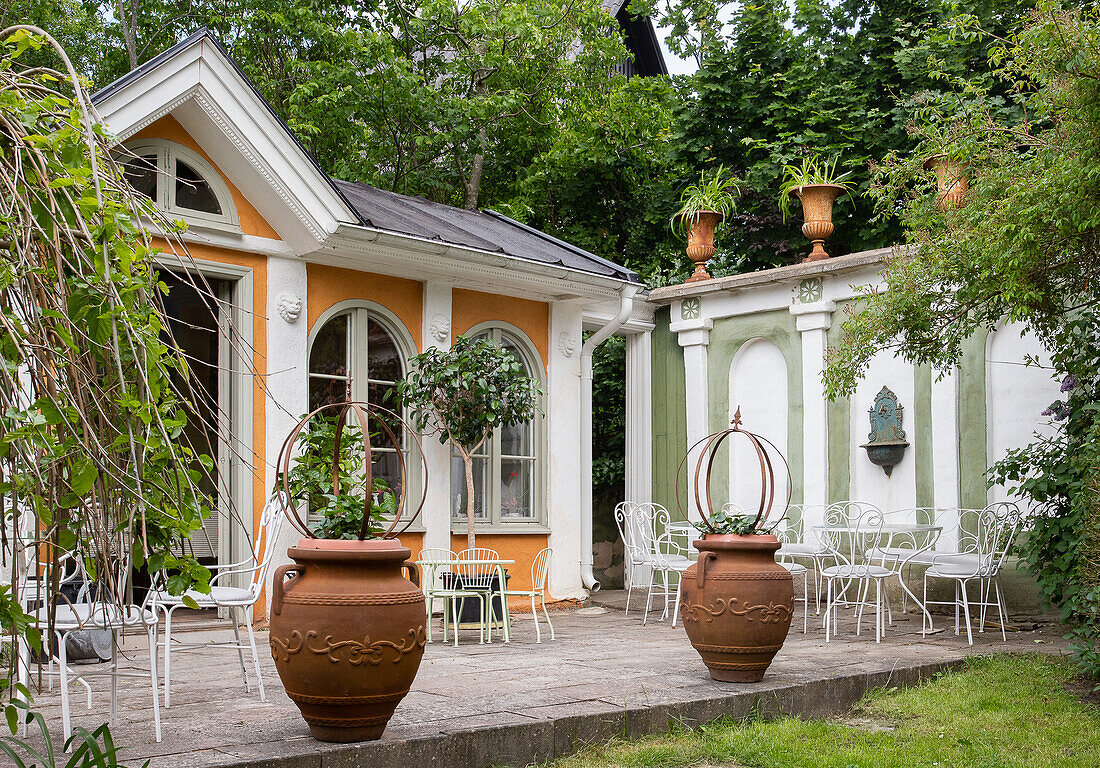 Terrace with terracotta pots in front of the orangery and garden wall