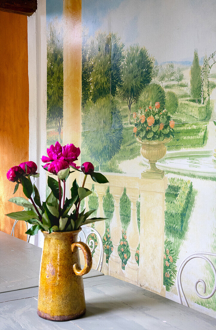 Orangery with a jug vase with peonies in front of Mediterranean mural