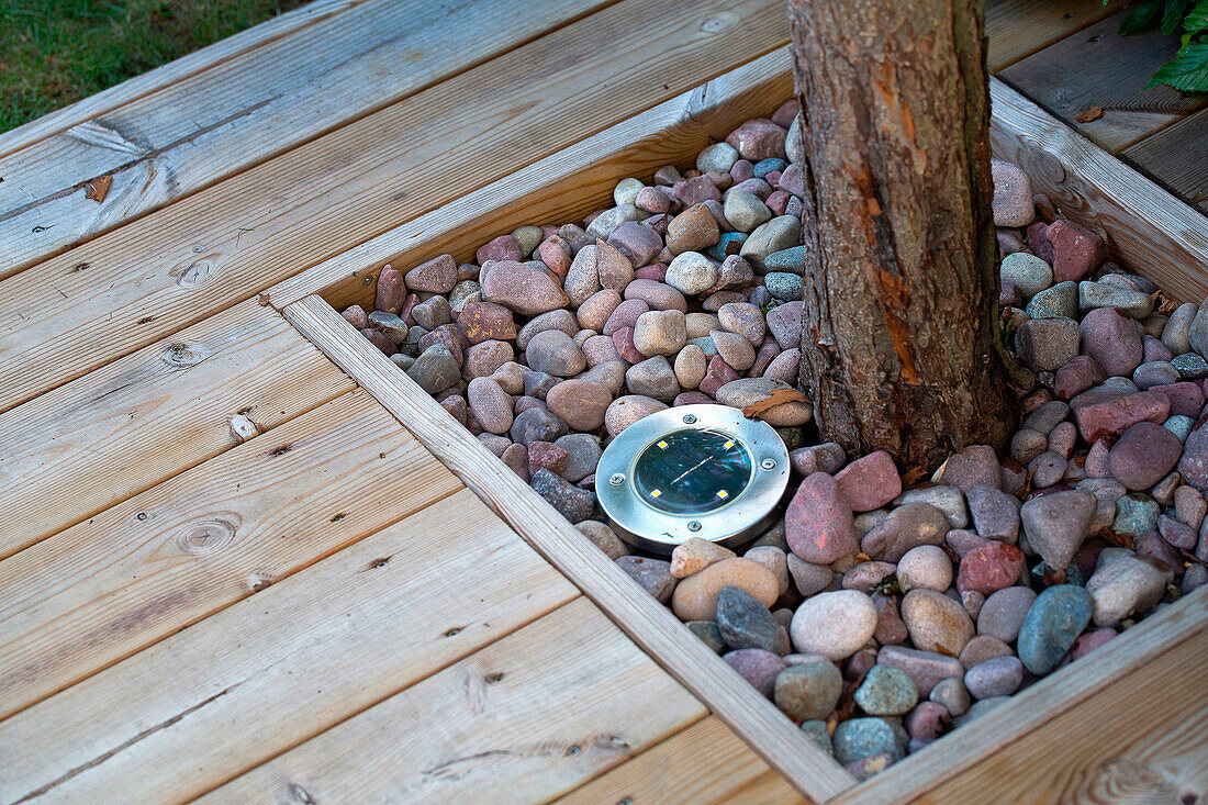 Holzterrasse mit integrierter Baumumrandung und Bodenleuchte