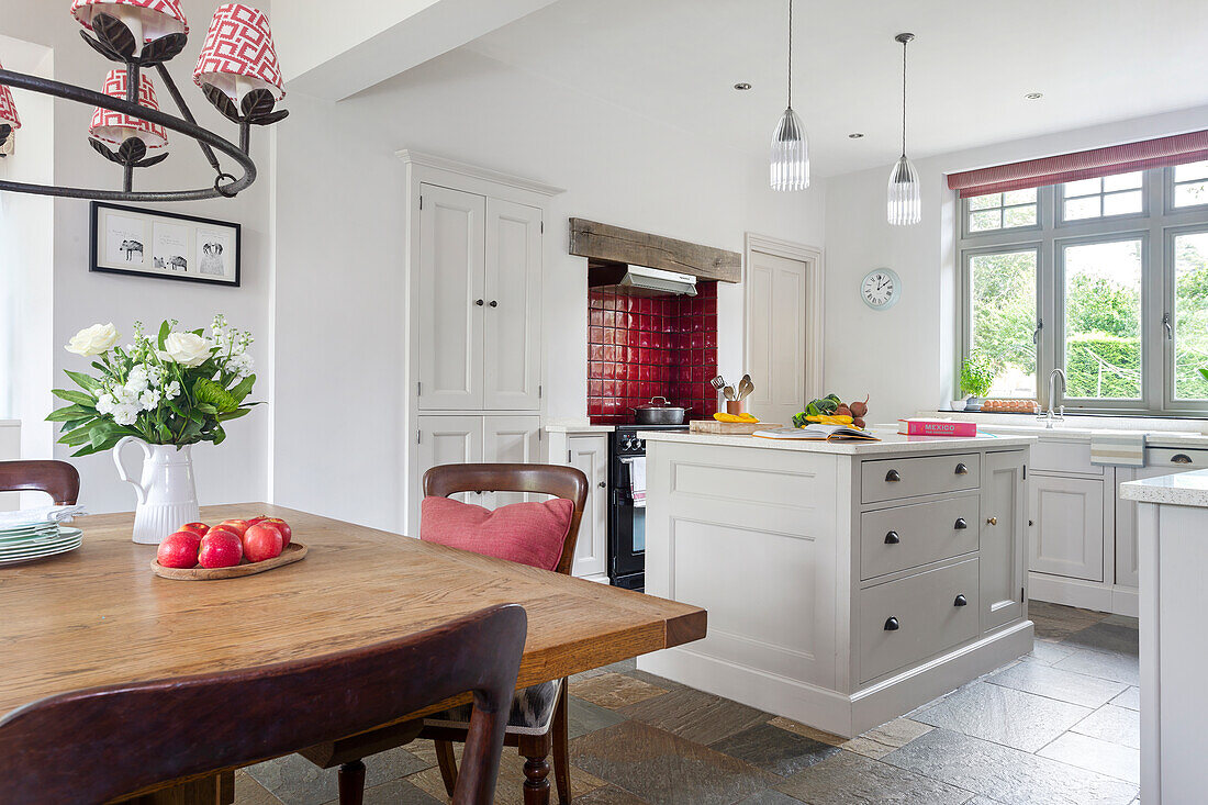 Bright country kitchen with island, wooden table and red accents