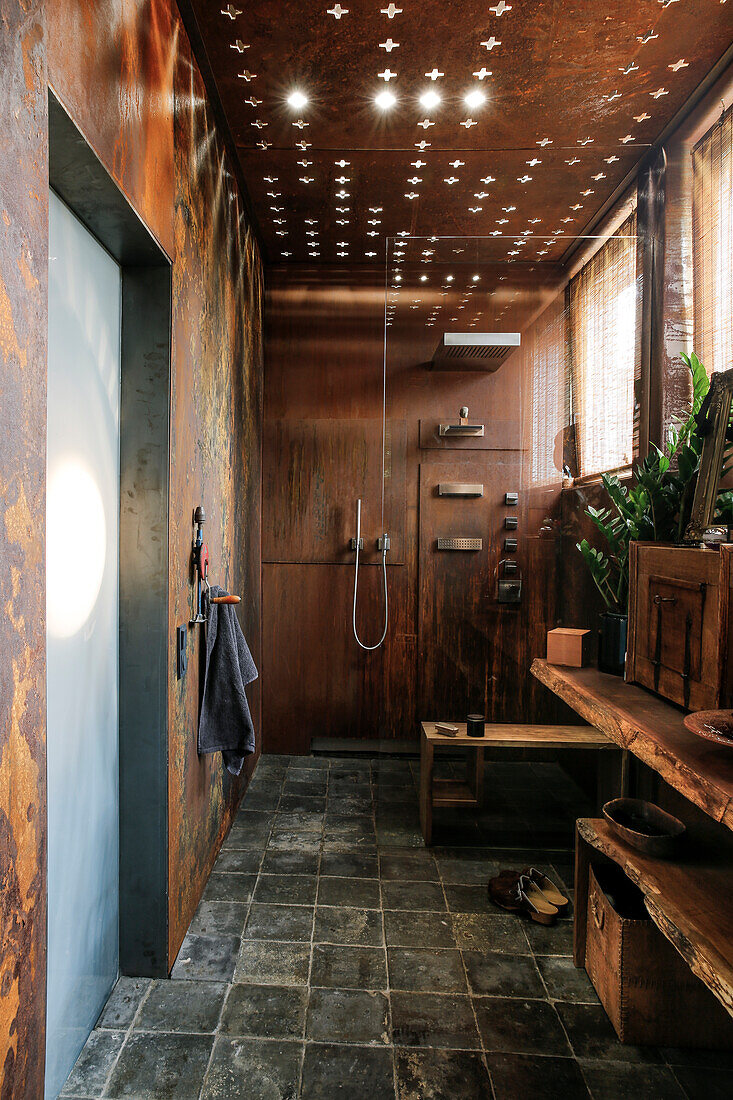 Modernes Badezimmer mit Wandverkleidung aus Cortenstahl und Lichteffekten an der Decke