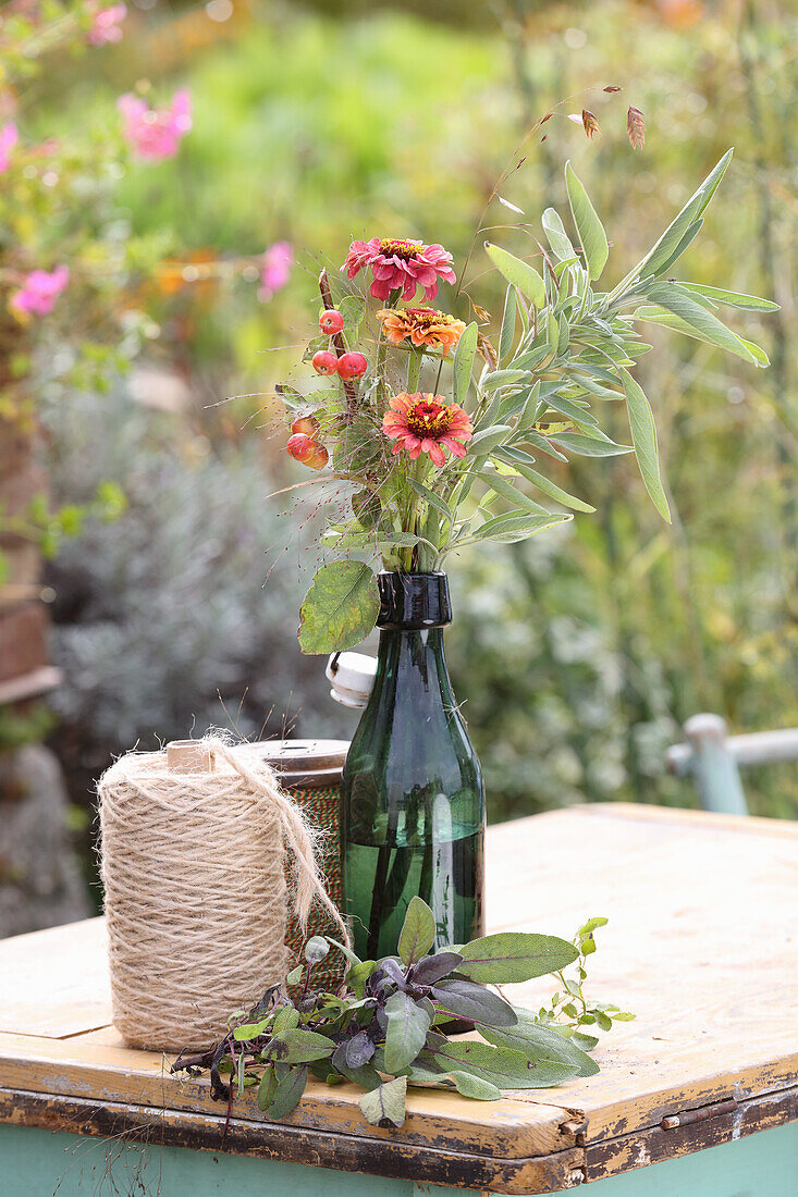 Zinnias with bouquet grasses Flat ear grass, sage and berry branch in vintage shackle bottle
