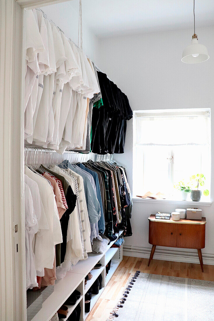 Walk-in wardrobe in minimalist bedroom with retro chest of drawers