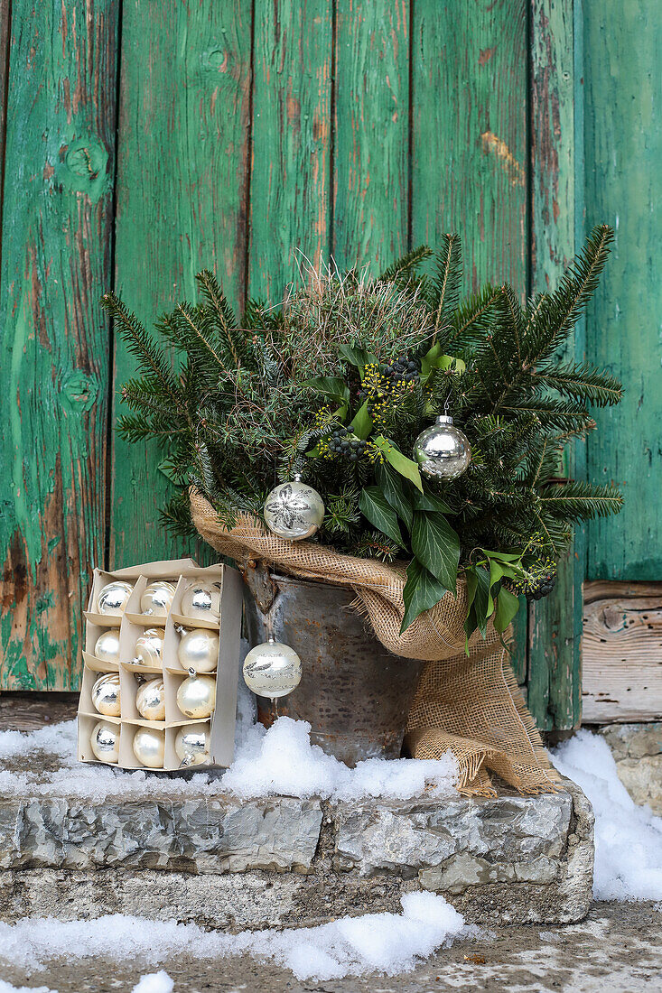 Winter bouquet with Christmas baubles and jute ribbon in a tin bucket