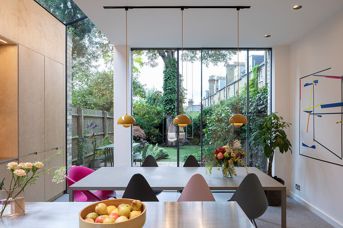 Open-plan kitchen with island counter and dining area: view through glazing into the garden