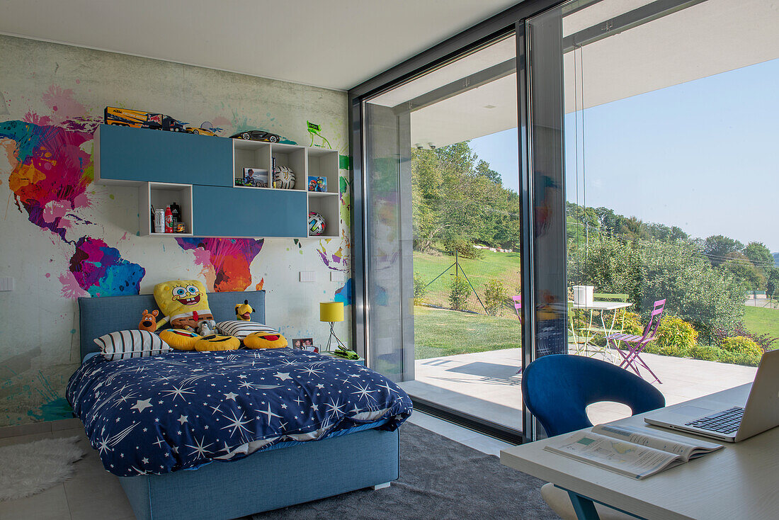 Modern children's room with wall painting, large window front and view of the greenery