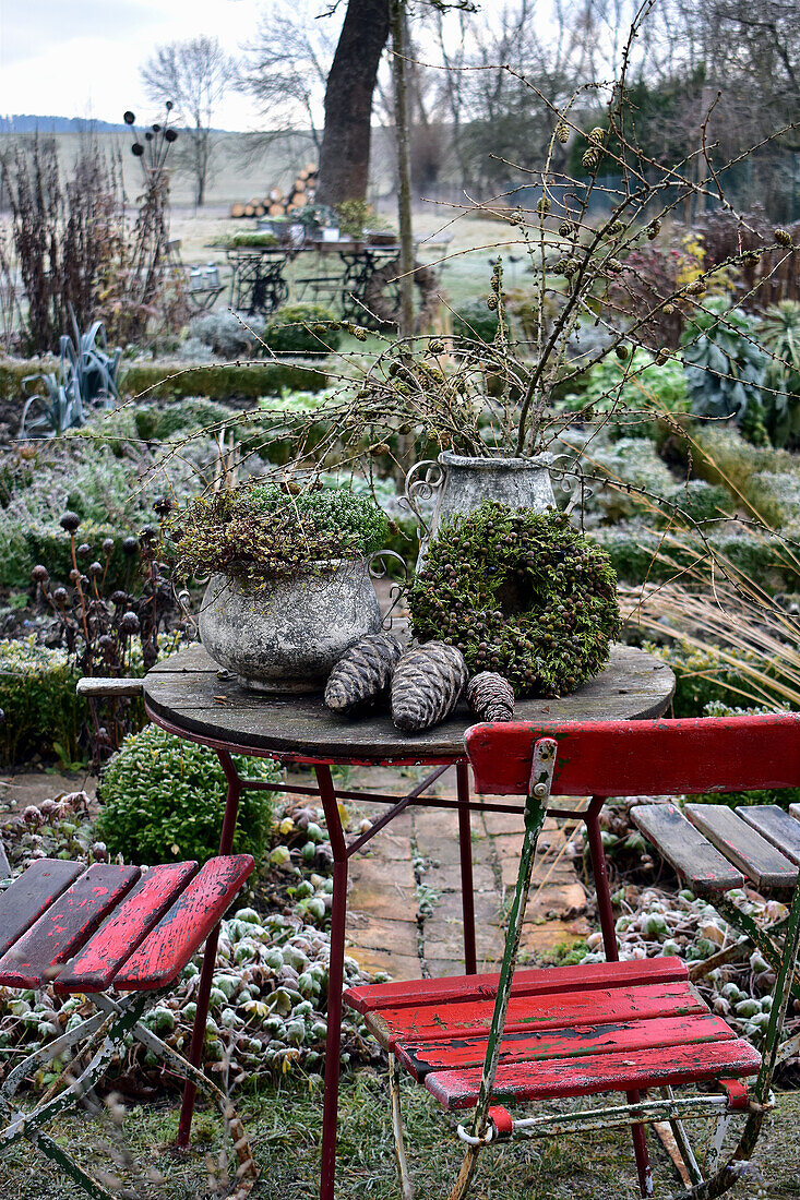 Steintöpfe, Lärchenzweige und Lebensbaumkranz auf Gartentisch