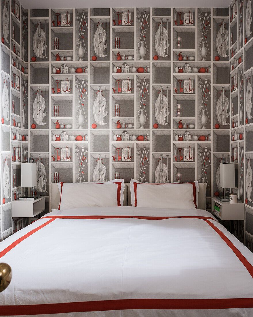 Double bed with red and white bed linen in bedroom with trompe l'oeil wallpaper