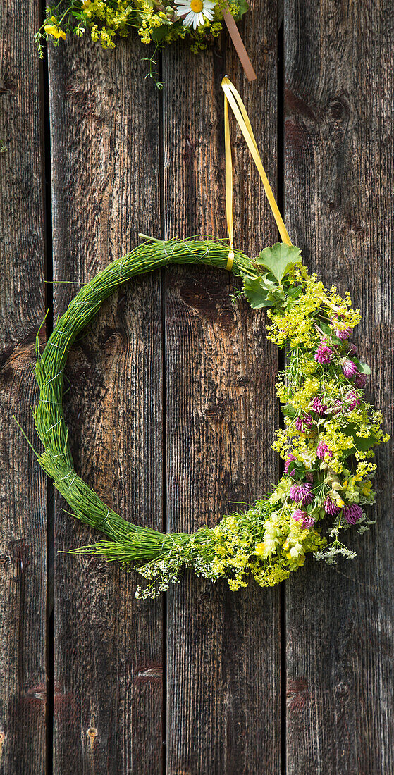 Blumenkranz mit Wildblumen an einer Holzwand