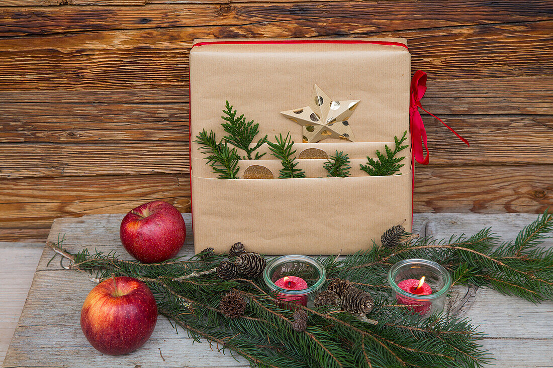 Gift made from natural wrapping paper, fir branches, apples and tea lights