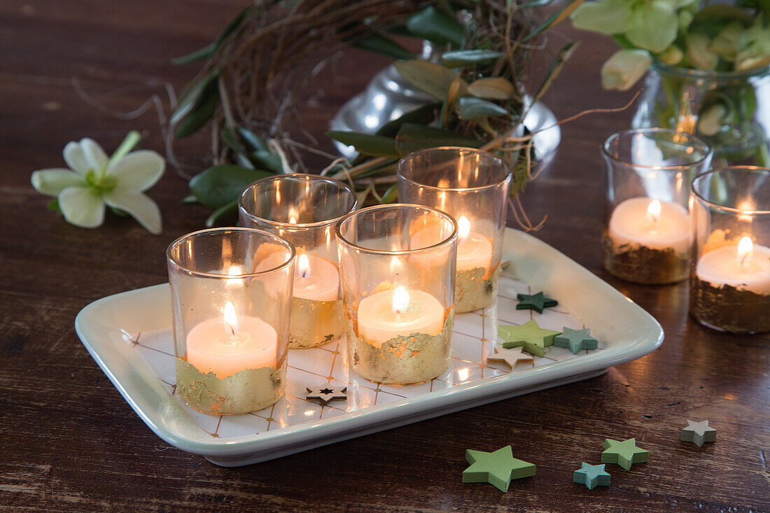 Candles in gold-rimmed glasses on a tray with star decoration