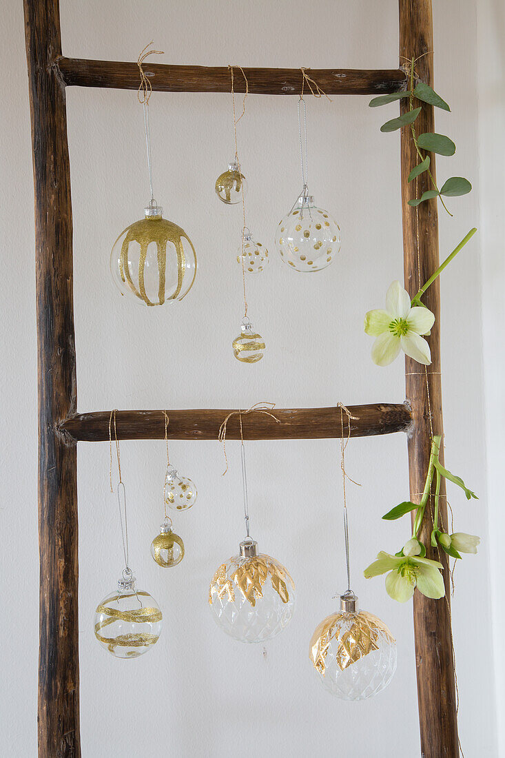 Wooden ladder with gold-decorated glass baubles and flowers