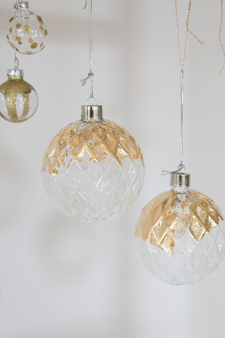 Glass Christmas baubles with gold paint against a white background