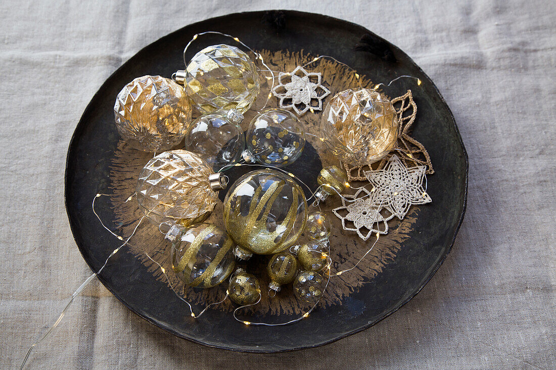 Christmas baubles, crocheted stars and fairy lights in a bowl