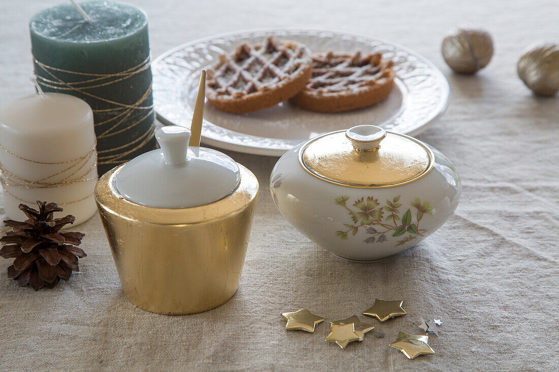 Weihnachtlich gedeckter Tisch mit Kerzen, Gebäck und Zuckerdosen