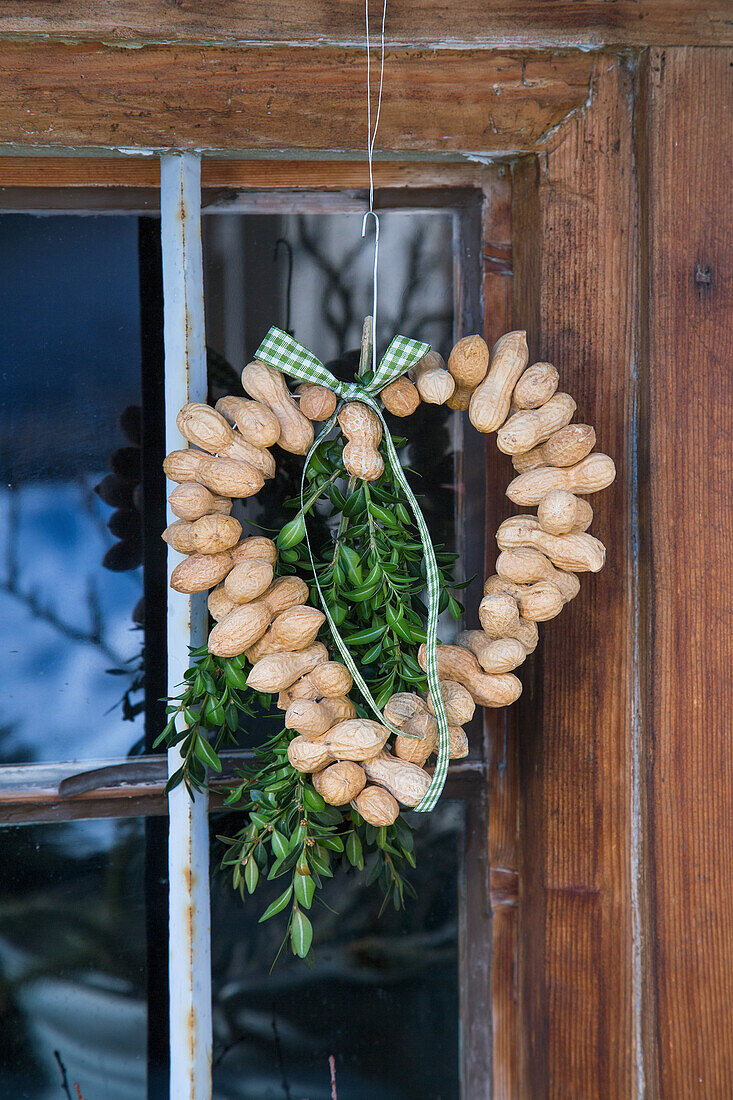 DIY door wreath made from peanuts with green branches and ribbon