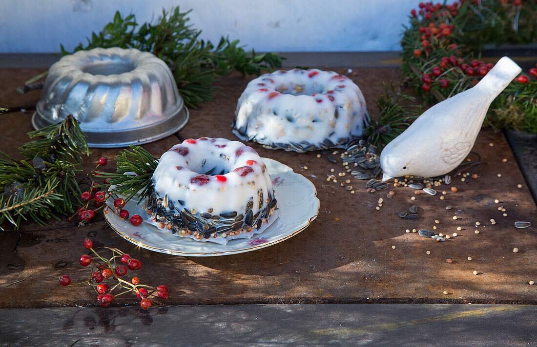 Bird feeder in mini bundt cake moulds on a wooden table with winter decorations