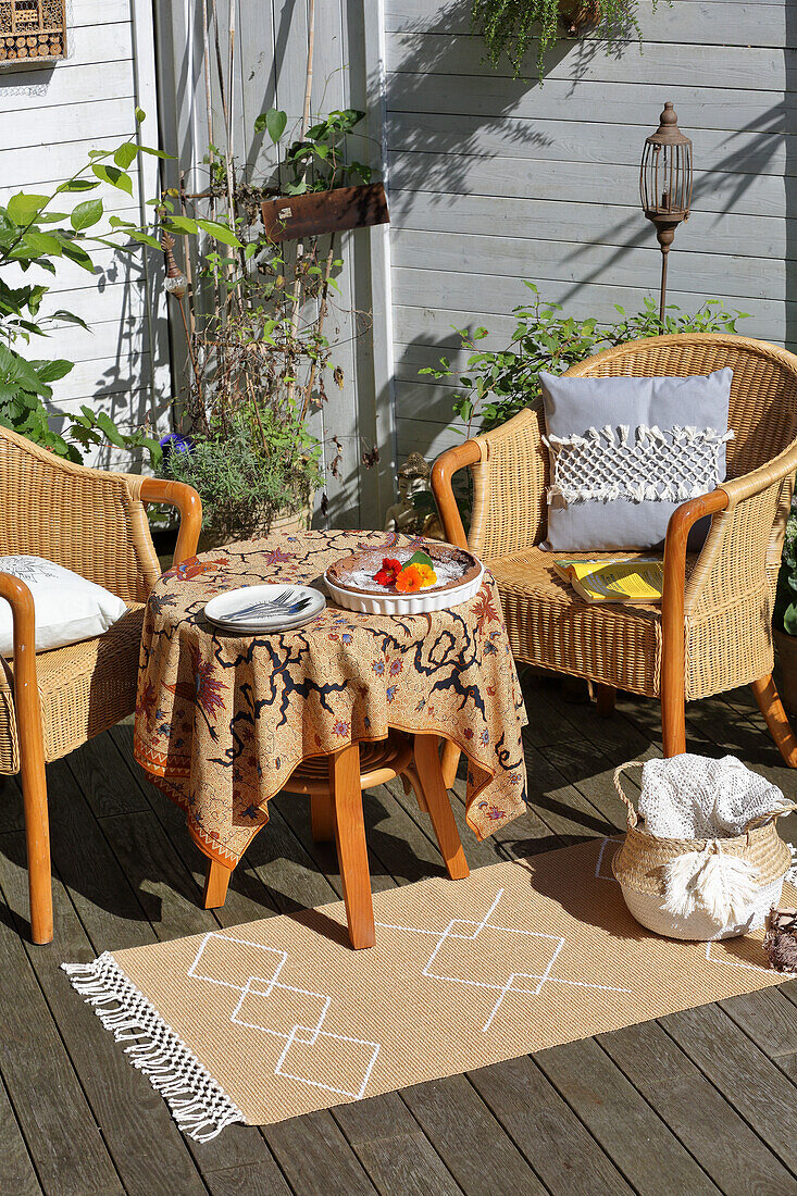 Korbsessel mit Tisch und Teppich auf Terrasse, Accessoires mit DIY-Verzierung