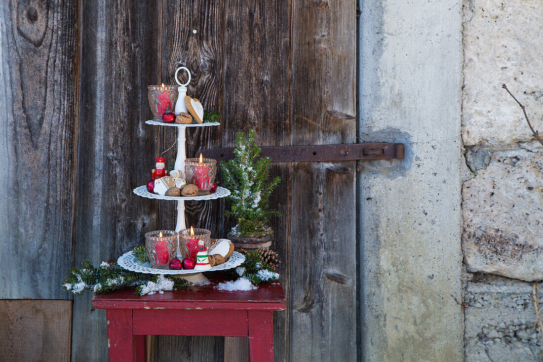 Romantic etagere with lanterns, red balls, walnuts and gingerbread outdoors