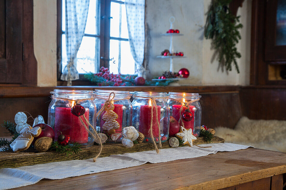 Red candles in jam jars, decorated with gingerbread and Christmas ornaments