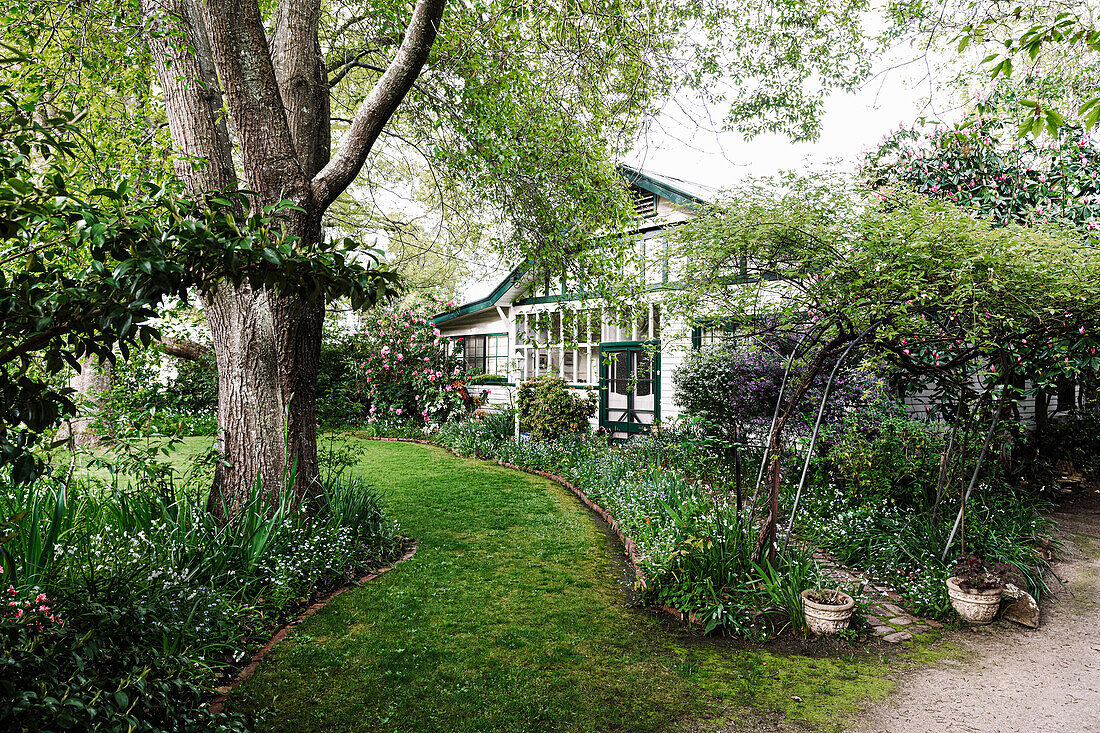 Fachwerkhaus im Garten mit Rasen und Blumenbeeten