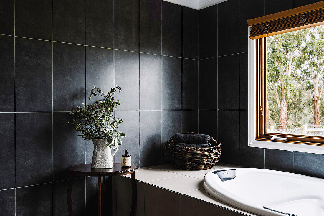 Black vertical tiles in rustic bathroom with oval bathtub