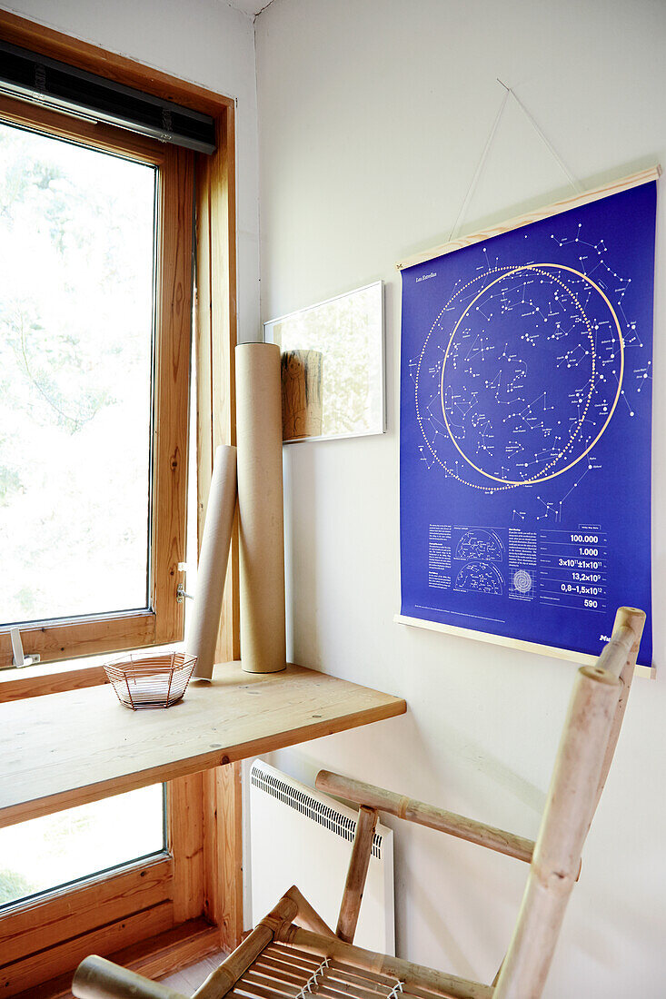 Small workplace with bamboo chair in front of the window, wall map with starry sky