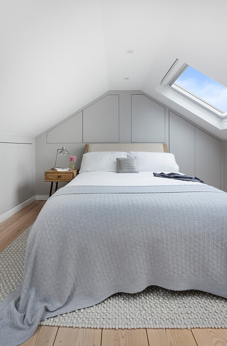 Doppelbett mit grauer Tagesdecke im Schlafzimmer im Dachgeschoß
