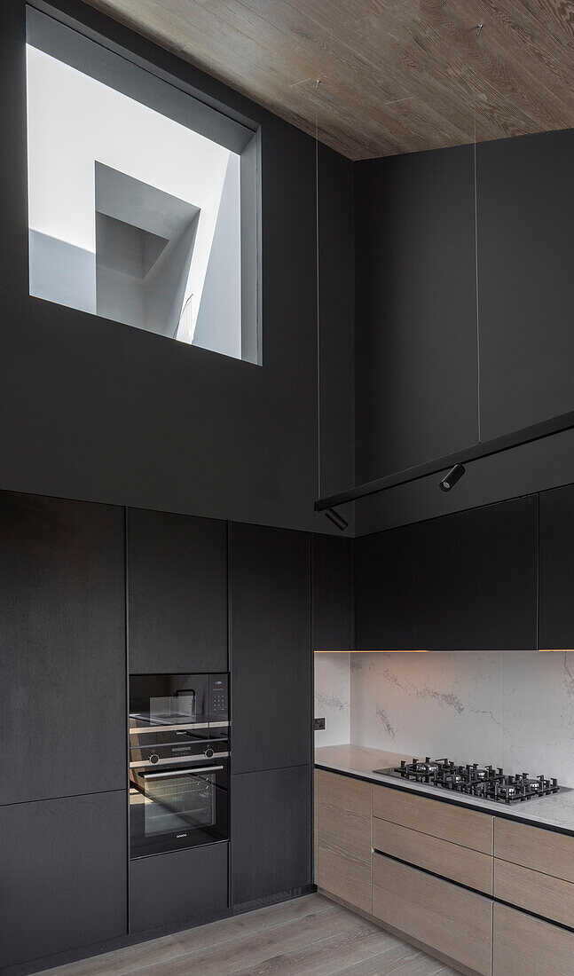Minimalistische Küche mit schwarzen Wänden und Innenfenster