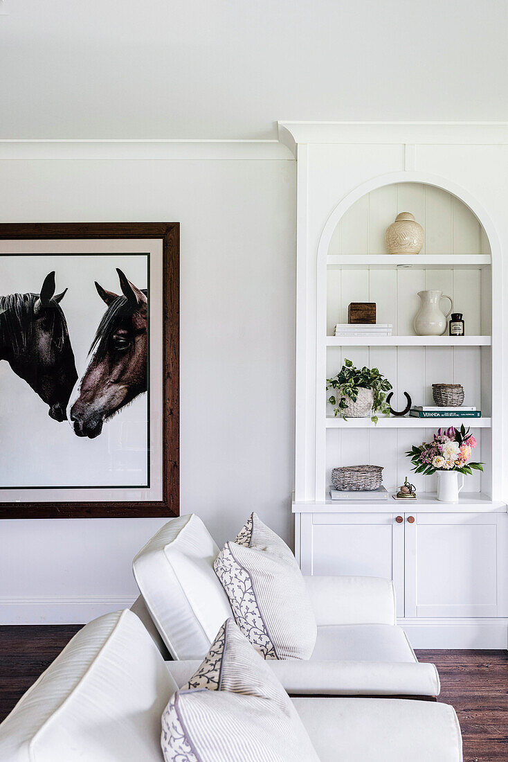 Weiße Sessel, Einbauregal in Wandnische und eingerahmtes Pferdefoto im Wohnzimmer