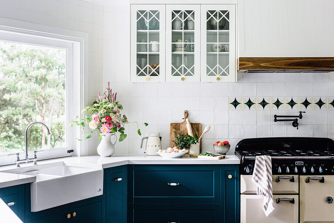 Renovierte Landhausküche mit weißer Fliesenwand und petrolfarbenen Unterschränken