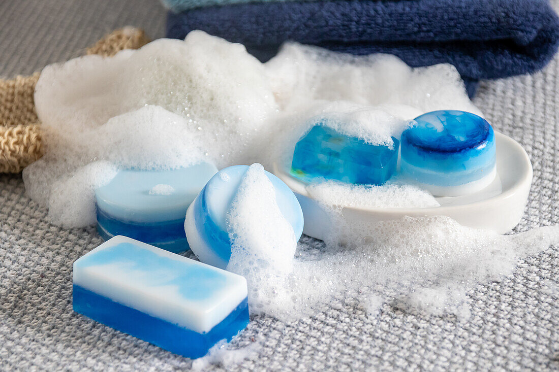 Handmade soap bars with foam on a grey towel