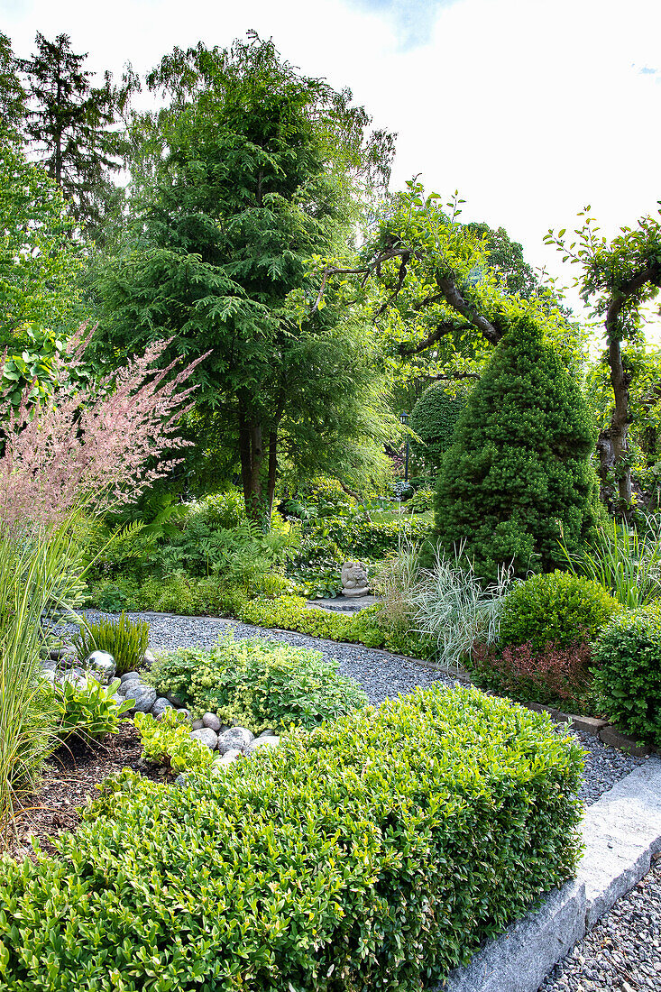 Vielfältig bepflanzter Garten mit Kiesweg