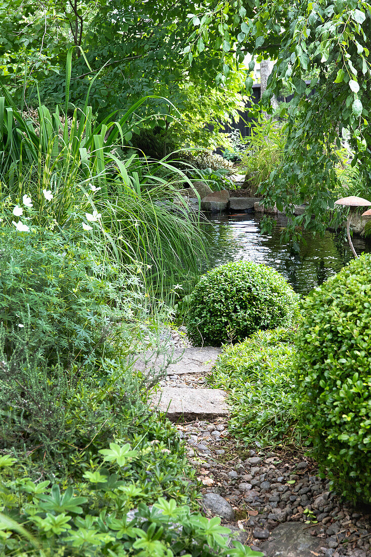 Gartenpfad aus Kieselsteinen und Teich im Hintergrund