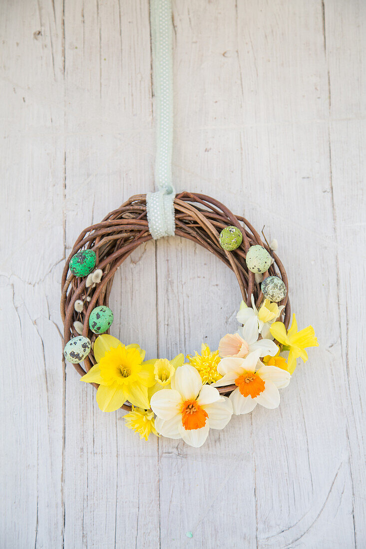 Wicker wreath decorated for Easter on a white wall
