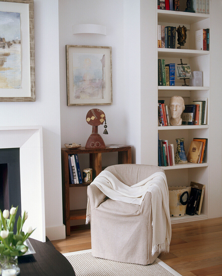 A detail of a traditional living room seat covered in neutral fabric built in bookshelves
