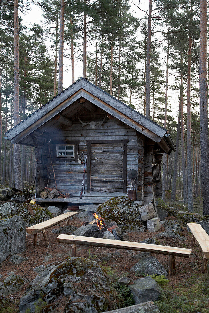 Sitzbänke am offenen Feuer in einer Jagdhütte im Wald von Svartadalen in Schweden