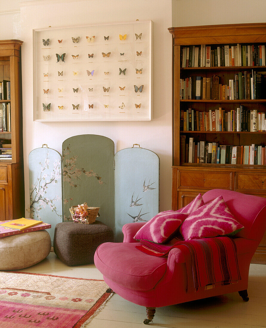 A traditional living room framed butterflies above a painted screen with swallows wooden bookshelf upholstered armchair